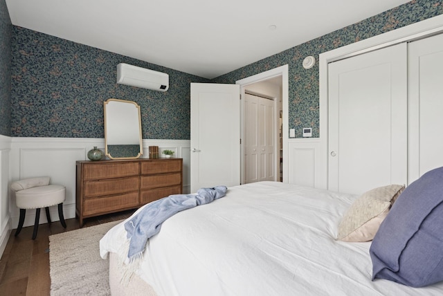 218 Washington Ave Unit 107, Portland, ME 04101 - bedroom with a wall mounted air conditioner, a wainscoted wall, wallpapered walls, wood finished floors, and a closet