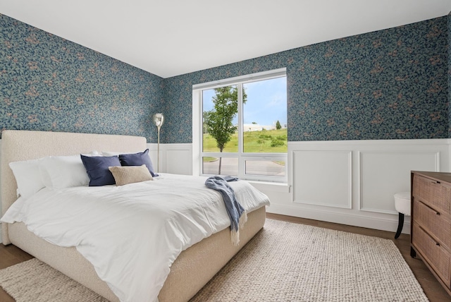 218 Washington Ave Unit 107, Portland, ME 04101 - bedroom featuring wallpapered walls, a wainscoted wall, wood finished floors, and a decorative wall
