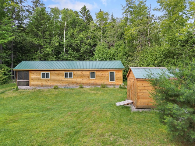 92 Cottage Shore Dr, Holden, ME 04429 - rear view of property featuring a metal roof, a shed, a yard, a sunroom, and a wooded view