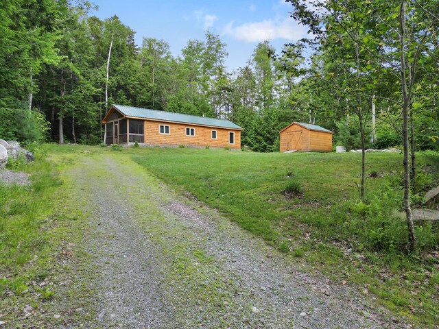 92 Cottage Shore Dr, Holden, ME 04429 - view of front of house with a sunroom, a storage shed, driveway, a front lawn, and a metal roof