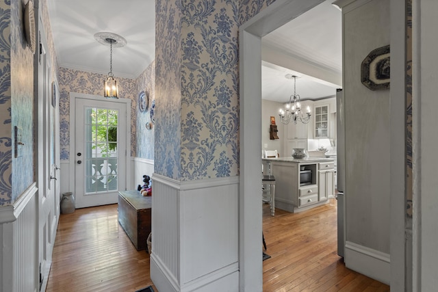18 High St, Wiscasset, ME 04578 - foyer featuring wallpapered walls, wainscoting, a chandelier, crown molding, and light wood-style floors