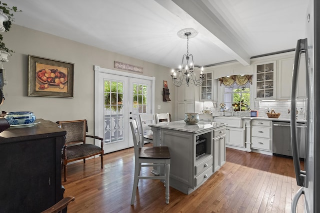 18 High St, Wiscasset, ME 04578 - kitchen with a chandelier, beamed ceiling, hardwood / wood-style flooring, white cabinets, and glass insert cabinets