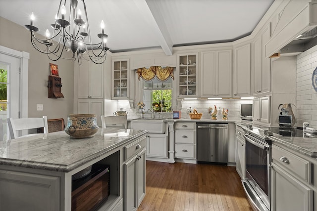 18 High St, Wiscasset, ME 04578 - kitchen with appliances with stainless steel finishes, a chandelier, beam ceiling, backsplash, and light stone counters