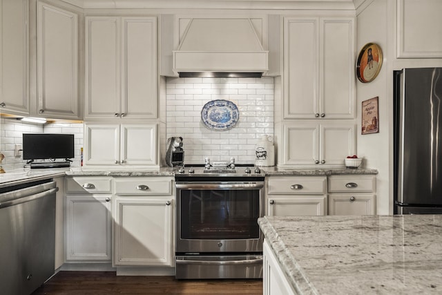 18 High St, Wiscasset, ME 04578 - kitchen with stainless steel appliances, custom range hood, decorative backsplash, and light stone counters