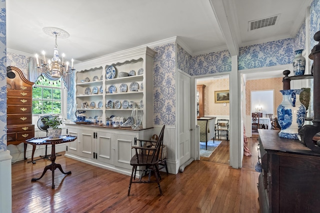 18 High St, Wiscasset, ME 04578 - dining room with wallpapered walls, wood-type flooring, a chandelier, a wainscoted wall, and crown molding