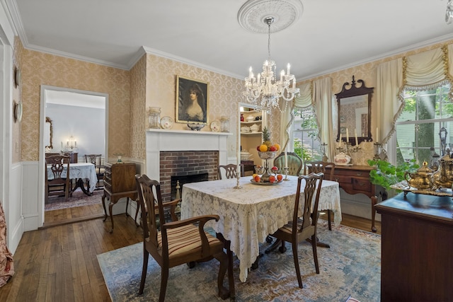 18 High St, Wiscasset, ME 04578 - dining space with wallpapered walls, hardwood / wood-style floors, crown molding, a brick fireplace, and a chandelier