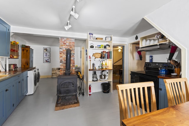 141 Centre St, Bath, ME 04530 - kitchen featuring a wood stove, open shelves, black range with electric cooktop, and washing machine and clothes dryer
