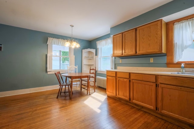 25 Oliver St, Bath, ME 04530 - kitchen with radiator, a chandelier, light wood finished floors, light countertops, and brown cabinets