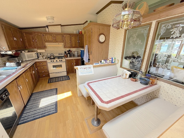 8 Bar Is, Tremont, ME 04674 - kitchen with white appliances, wallpapered walls, under cabinet range hood, light wood finished floors, and brown cabinetry