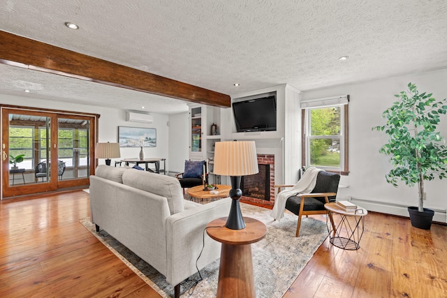 13 Wildbrook Dr, Biddeford, ME 04005 - living room featuring a textured ceiling, a baseboard radiator, a wall mounted AC, hardwood / wood-style flooring, and a fireplace