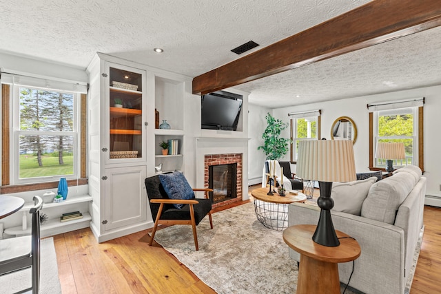 13 Wildbrook Dr, Biddeford, ME 04005 - living room with a textured ceiling, light wood-style floors, a brick fireplace, beam ceiling, and a baseboard heating unit