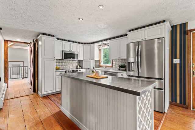 13 Wildbrook Dr, Biddeford, ME 04005 - kitchen featuring stainless steel appliances, light wood-style flooring, white cabinets, a textured ceiling, and tasteful backsplash