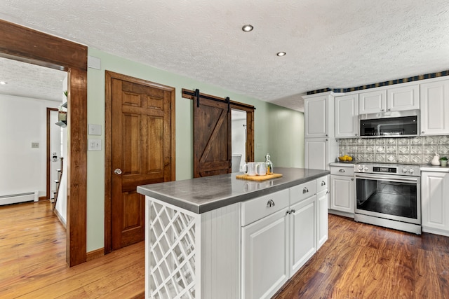 13 Wildbrook Dr, Biddeford, ME 04005 - kitchen with stainless steel appliances, a textured ceiling, a barn door, white cabinetry, and light wood-style flooring