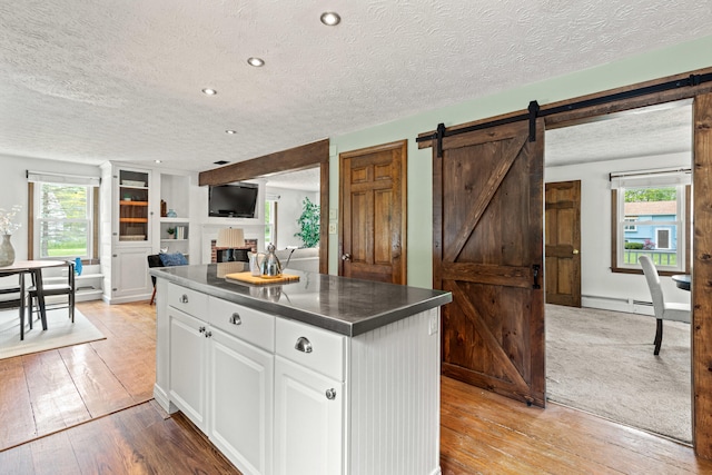 13 Wildbrook Dr, Biddeford, ME 04005 - kitchen with a textured ceiling, white cabinetry, light wood-style flooring, a center island, and healthy amount of natural light