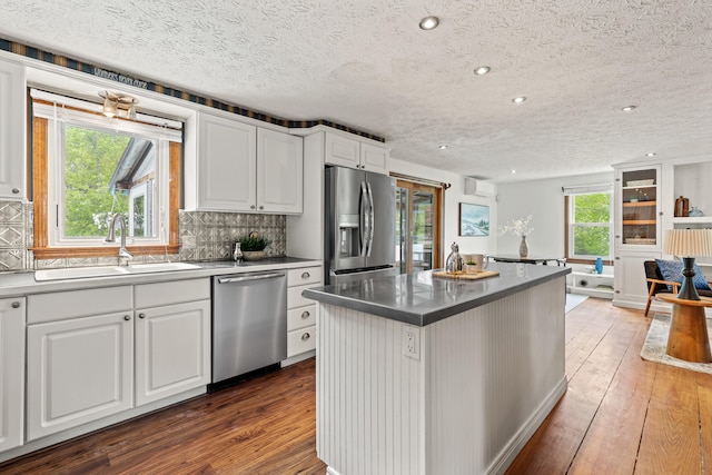 13 Wildbrook Dr, Biddeford, ME 04005 - kitchen featuring appliances with stainless steel finishes, hardwood / wood-style floors, a kitchen island, white cabinetry, and a textured ceiling