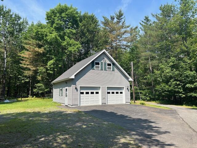 60 Dawes Rd, Dover-Foxcroft, ME 04426 - view of property exterior with a garage, a view of trees, and a yard