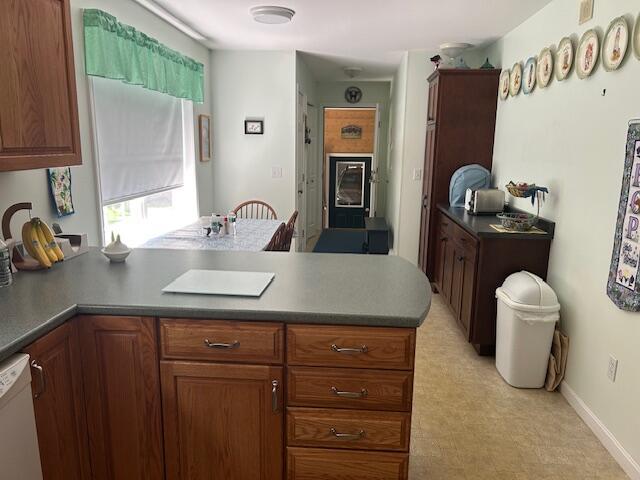 60 Dawes Rd, Dover-Foxcroft, ME 04426 - kitchen with a peninsula, white dishwasher, light floors, dark countertops, and brown cabinets
