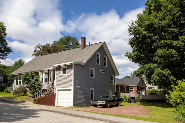 99 Gamage Ave, Auburn, ME 04210 - view of side of home with a chimney, a garage, and stairway