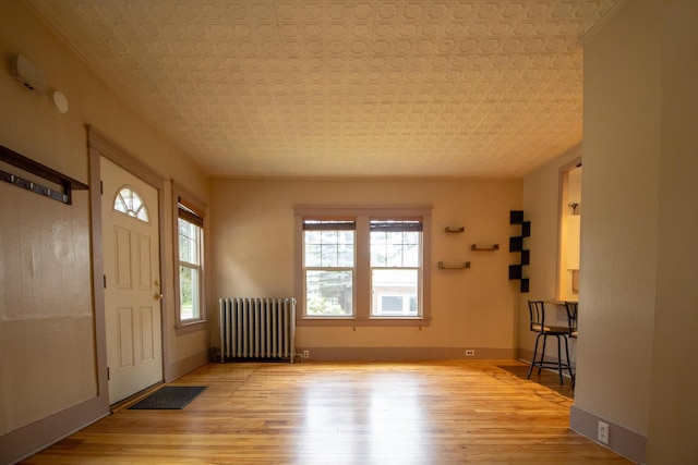 99 Gamage Ave, Auburn, ME 04210 - entrance foyer featuring radiator heating unit, light wood-style flooring, and an ornate ceiling