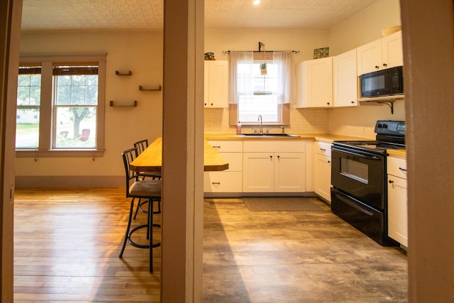 99 Gamage Ave, Auburn, ME 04210 - kitchen featuring black appliances, light wood-type flooring, white cabinets, light countertops, and backsplash