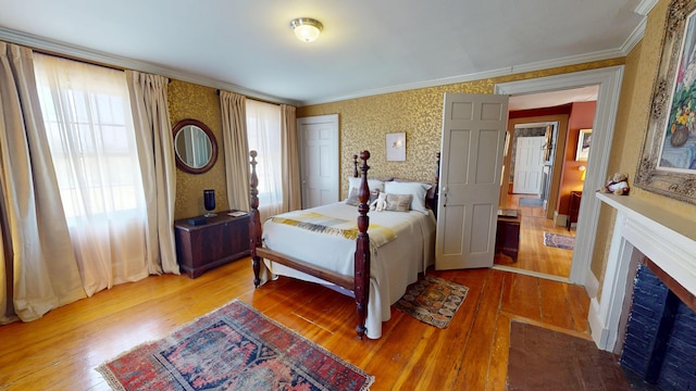 12 Center St, Machias, ME 04654 - bedroom with wallpapered walls, wood-type flooring, a fireplace with flush hearth, and ornamental molding
