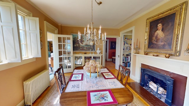 12 Center St, Machias, ME 04654 - dining room with radiator heating unit, a chandelier, wood finished floors, a fireplace with flush hearth, and crown molding