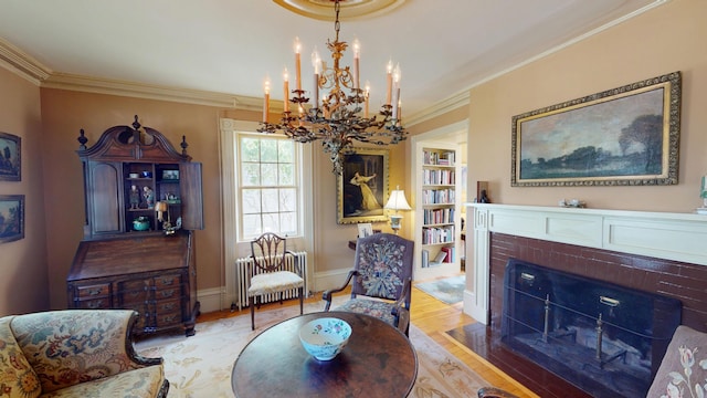 12 Center St, Machias, ME 04654 - living area with radiator heating unit, a brick fireplace, a chandelier, crown molding, and light wood finished floors