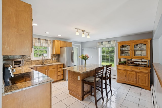 19 Straw Rd, Gorham, ME 04038 - kitchen with freestanding refrigerator, baseboard heating, a kitchen island, light stone counters, and backsplash