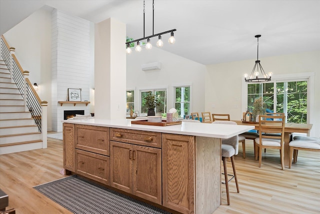 27 Meadow View Dr, Readfield, ME 04355 - kitchen with light wood-style floors, a chandelier, a large fireplace, a breakfast bar, and light countertops