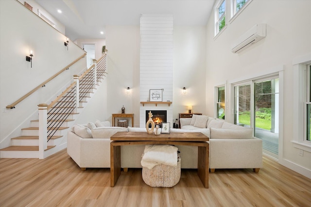 27 Meadow View Dr, Readfield, ME 04355 - living area featuring a wall mounted AC, light wood-type flooring, stairway, a towering ceiling, and a fireplace