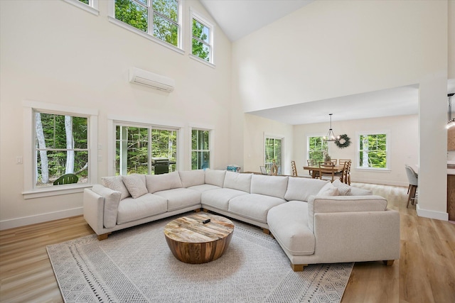 27 Meadow View Dr, Readfield, ME 04355 - living area with a wall unit AC, high vaulted ceiling, light wood-type flooring, and a chandelier