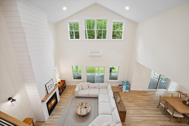 27 Meadow View Dr, Readfield, ME 04355 - living room featuring light wood-type flooring, a wall unit AC, a warm lit fireplace, high vaulted ceiling, and recessed lighting
