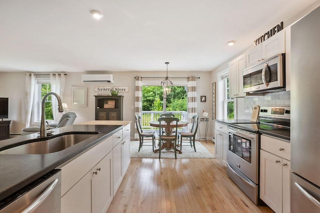 136-138 Blue Spruce Farm Rd, Westbrook, ME 04092 - kitchen with stainless steel appliances, a wall unit AC, white cabinetry, dark countertops, and light wood-style floors