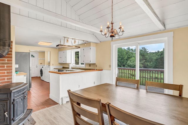 1511 Alna Rd, Alna, ME 04535 - dining area featuring a wood stove, washing machine and dryer, a chandelier, and light wood finished floors