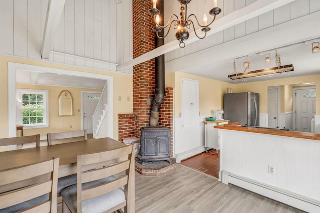 1511 Alna Rd, Alna, ME 04535 - dining space featuring a baseboard radiator, wood finished floors, a wood stove, stairway, and a chandelier