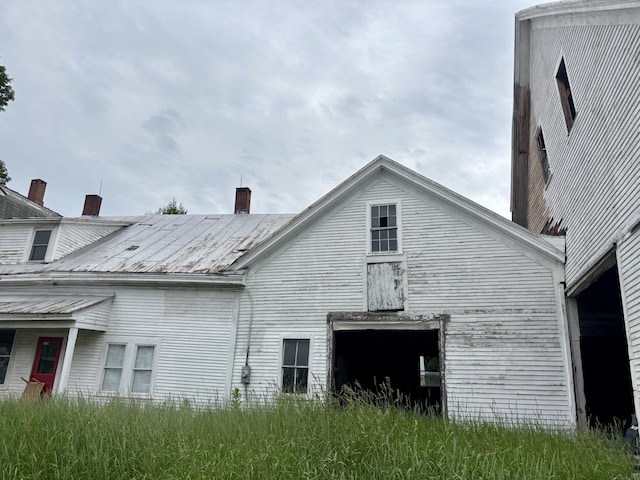 53 Main St, Phillips, ME 04966 - view of home's exterior featuring a chimney, a metal roof, and a garage