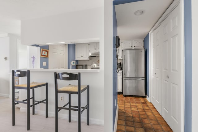 191 E Grand Ave Unit 506, Old Orchard Beach, ME 04064 - kitchen featuring freestanding refrigerator, a kitchen breakfast bar, under cabinet range hood, a peninsula, and stove