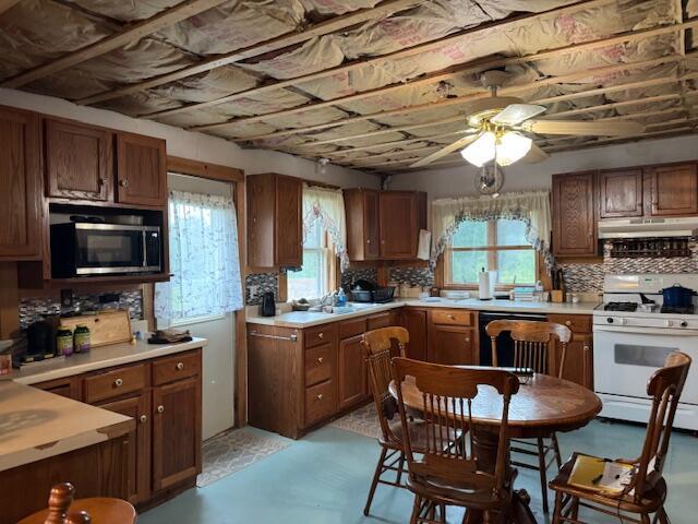 152 Cross Rd, Alna, ME 04535 - kitchen with white gas stove, stainless steel microwave, under cabinet range hood, ceiling fan, and dishwashing machine