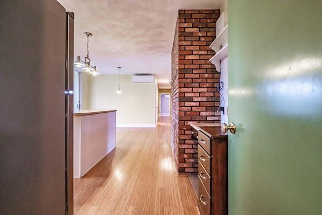 704 Brighton Hill Rd, Minot, ME 04258 - hallway with a wall unit AC, light wood-type flooring, and a textured ceiling
