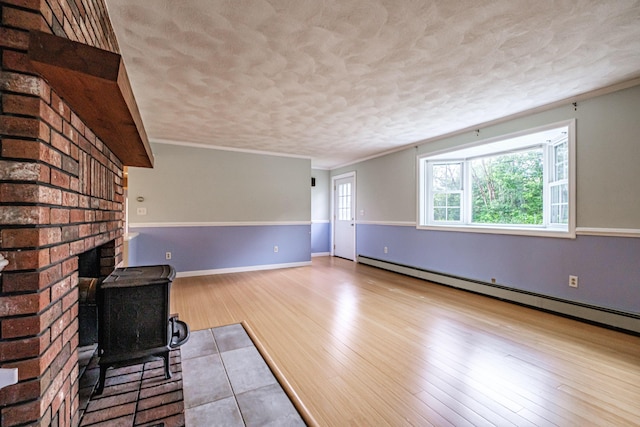 704 Brighton Hill Rd, Minot, ME 04258 - unfurnished living room featuring a baseboard radiator, a wood stove, a textured ceiling, wood finished floors, and ornamental molding