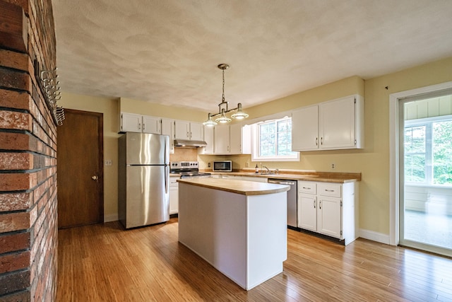 704 Brighton Hill Rd, Minot, ME 04258 - kitchen with appliances with stainless steel finishes, light wood-style floors, white cabinetry, decorative light fixtures, and a center island