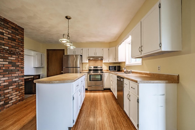 704 Brighton Hill Rd, Minot, ME 04258 - kitchen with appliances with stainless steel finishes, white cabinetry, light wood-style flooring, under cabinet range hood, and a center island