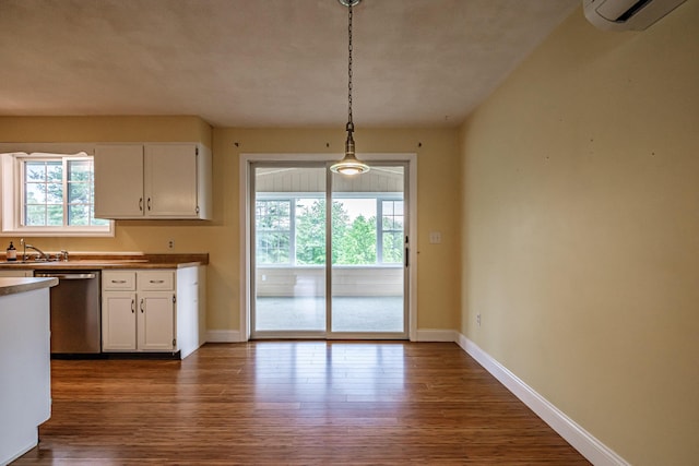 704 Brighton Hill Rd, Minot, ME 04258 - kitchen featuring stainless steel dishwasher, a wall unit AC, white cabinets, dark wood-style flooring, and hanging light fixtures