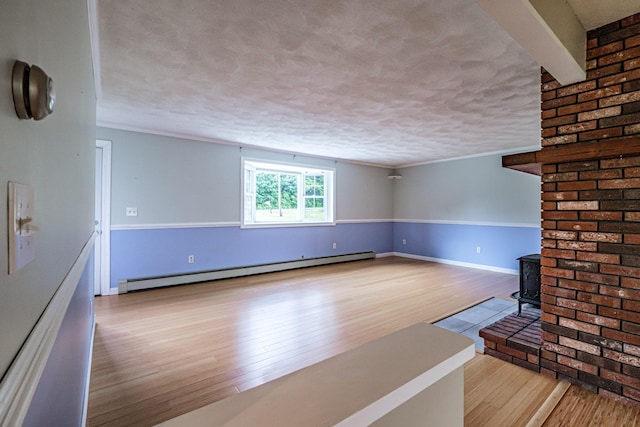 704 Brighton Hill Rd, Minot, ME 04258 - unfurnished living room featuring a baseboard heating unit, wood finished floors, a textured ceiling, and a wood stove