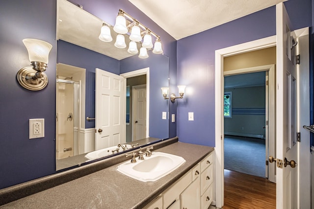 704 Brighton Hill Rd, Minot, ME 04258 - bathroom featuring a shower with shower door, baseboard heating, vanity, and wood finished floors