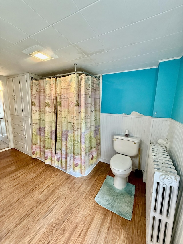 69 Lafayette St, Calais, ME 04619 - bathroom featuring radiator heating unit, wood finished floors, and a wainscoted wall