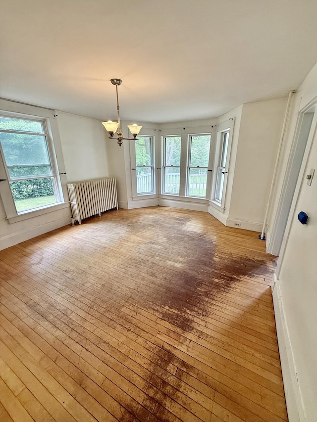 69 Lafayette St, Calais, ME 04619 - unfurnished room featuring radiator heating unit, light wood-style floors, and a chandelier