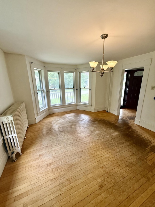 69 Lafayette St, Calais, ME 04619 - unfurnished dining area with light wood finished floors, a chandelier, and radiator