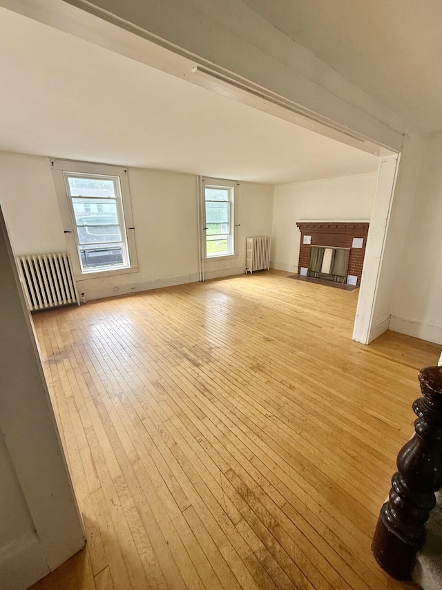 69 Lafayette St, Calais, ME 04619 - unfurnished living room with radiator heating unit, hardwood / wood-style flooring, and a fireplace