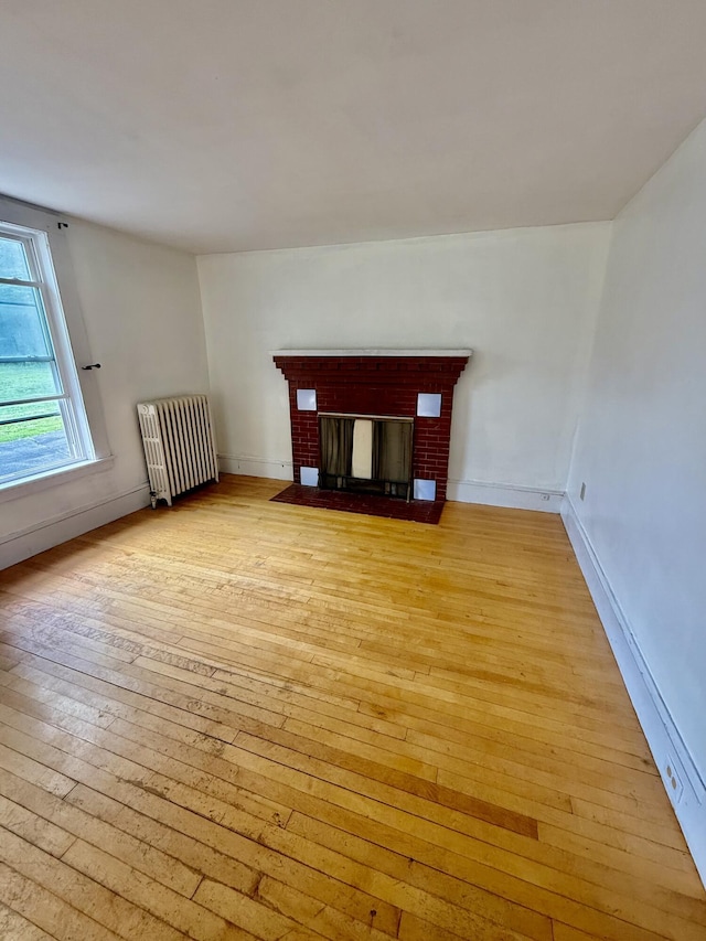 69 Lafayette St, Calais, ME 04619 - unfurnished living room with radiator heating unit, light wood finished floors, and a fireplace